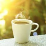 Dampfende Tasse Kaffee auf einem Tisch im warmen Morgenlicht als Symbol für ein neues Morgenritual ohne Zigarette.